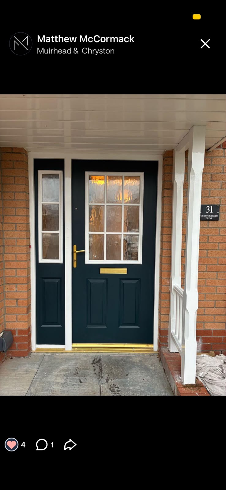 Dark green painted front door with a glazed side light and white porch post