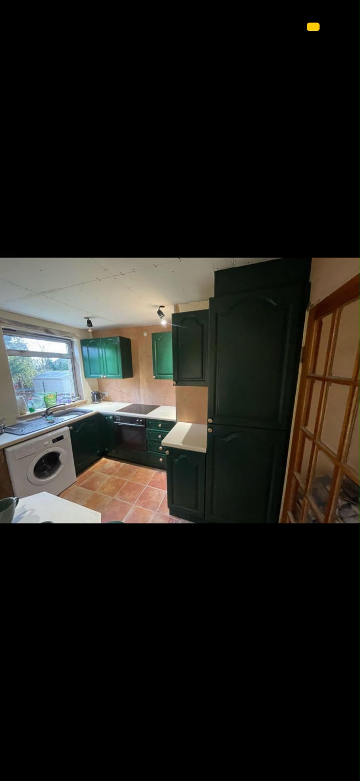 Green painted kitchen cupboards in a room being decorated